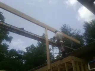 Carpenter setting a ridge beam over a new addition frame — Ice Dam Removal by Roofing Brothers in Blessing